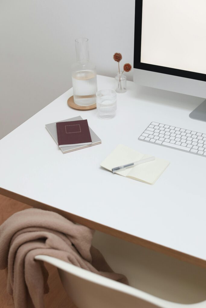 Workplace with wireless keyboard and monitor near notebooks on white wooden table in room